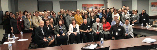 a large group of employees pose for a picture in a conference room